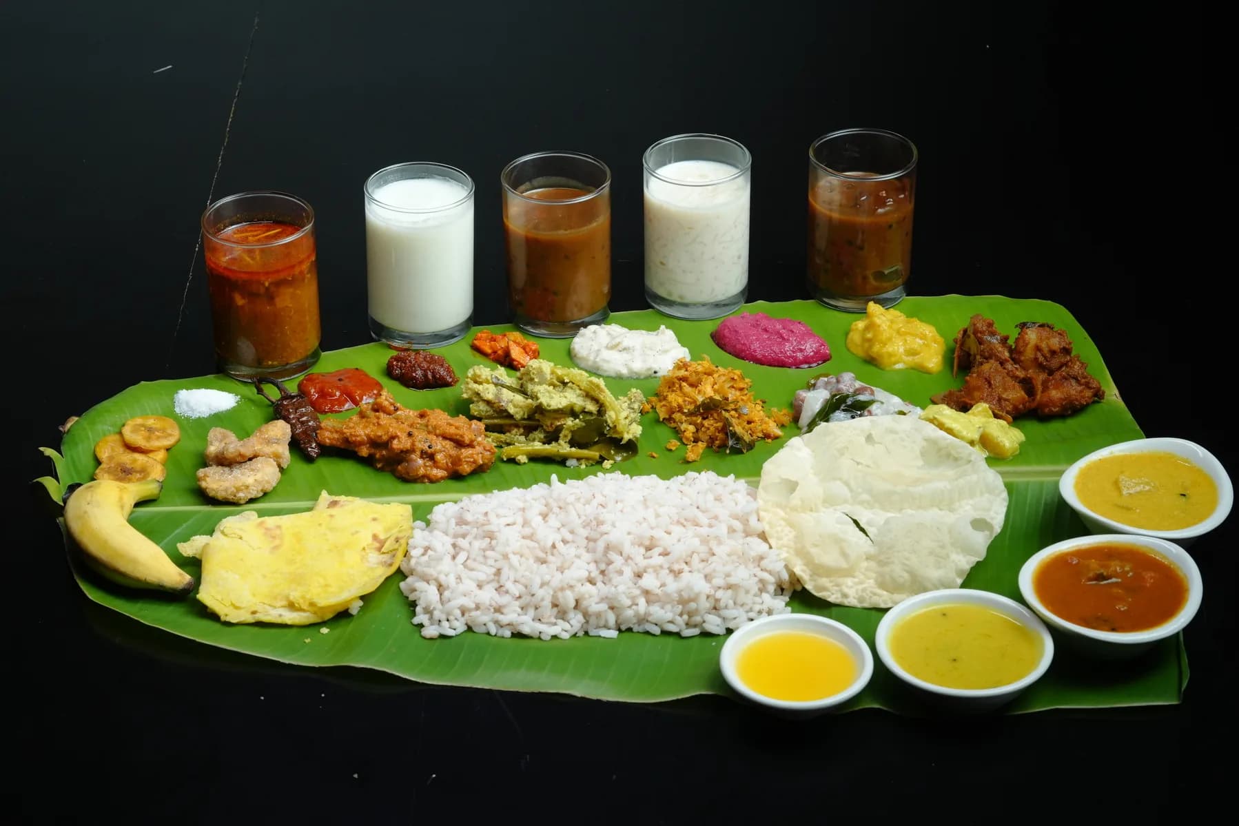 A full sadhya laid out on a banana leaf with rice, pickles, thoran and payasam.